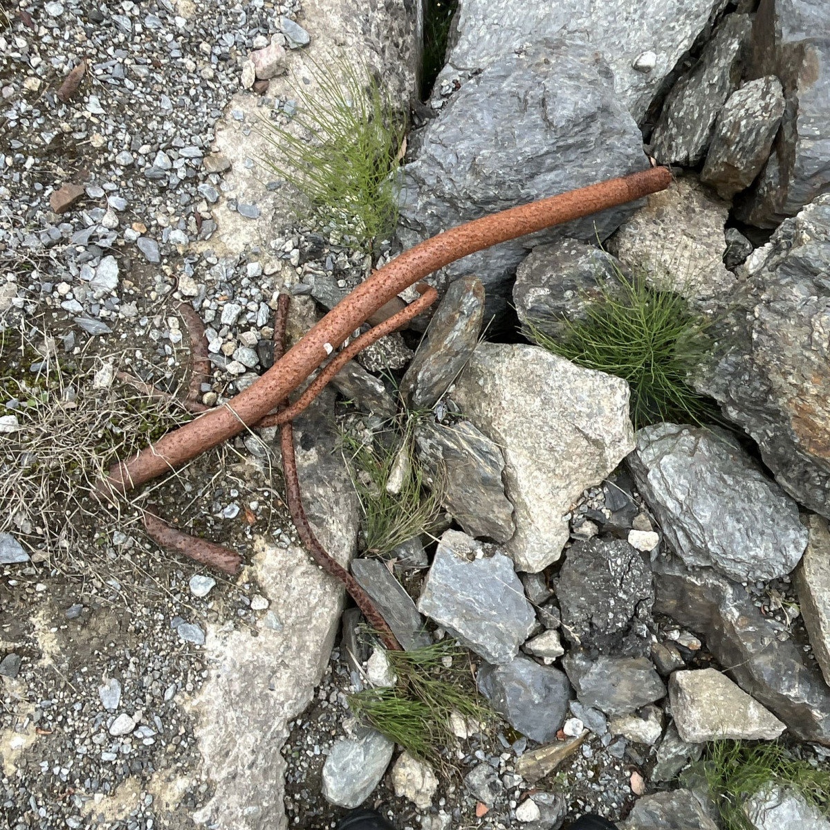 a metal rod in between rocks and concrete rubble